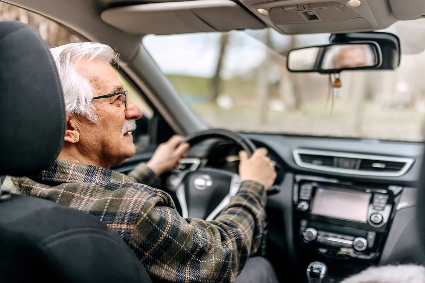 Senior male driver looking in the rearview mirror