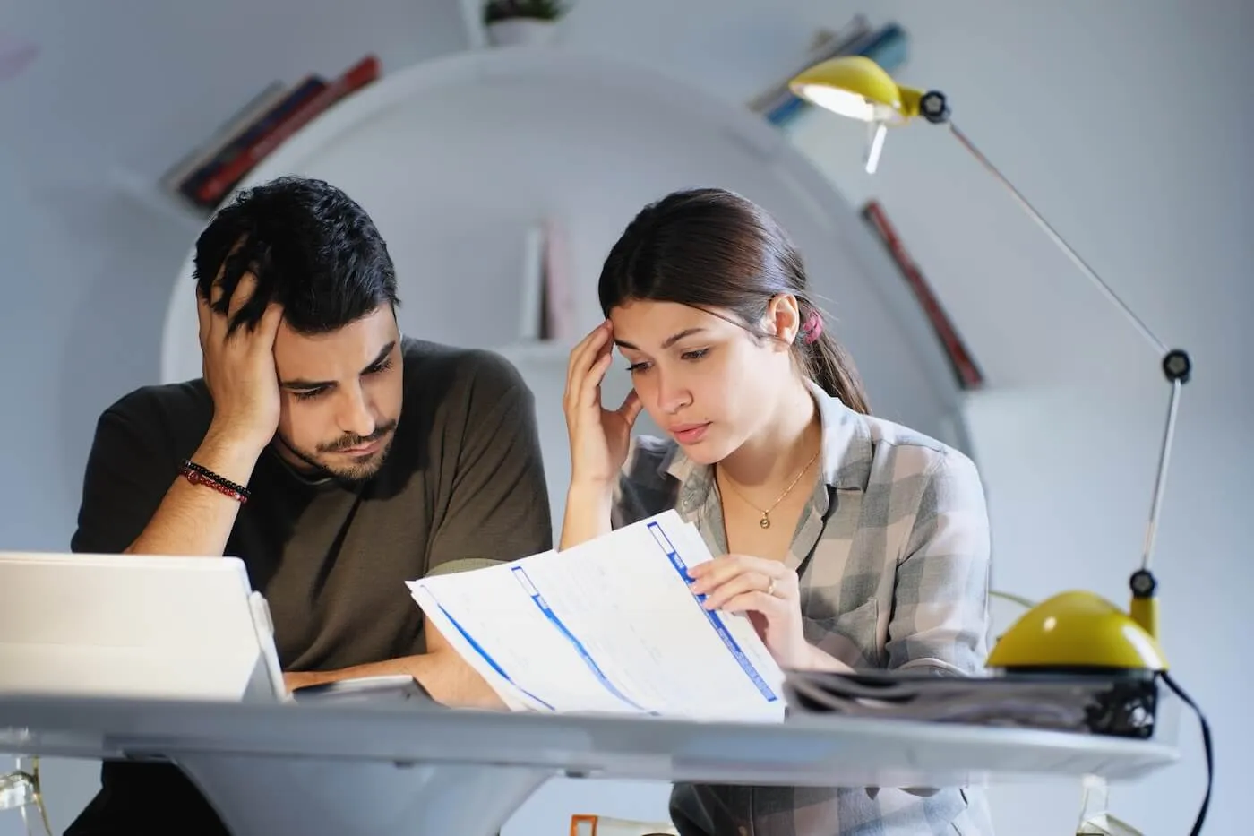 Concerned young couple reviewing their bills in a home office