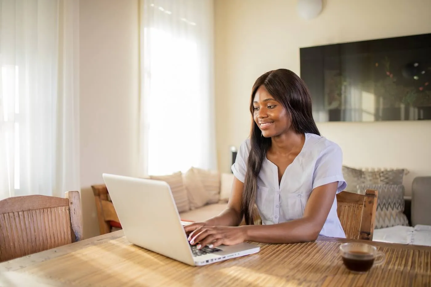 Smiling young woman using her laptop in the living room