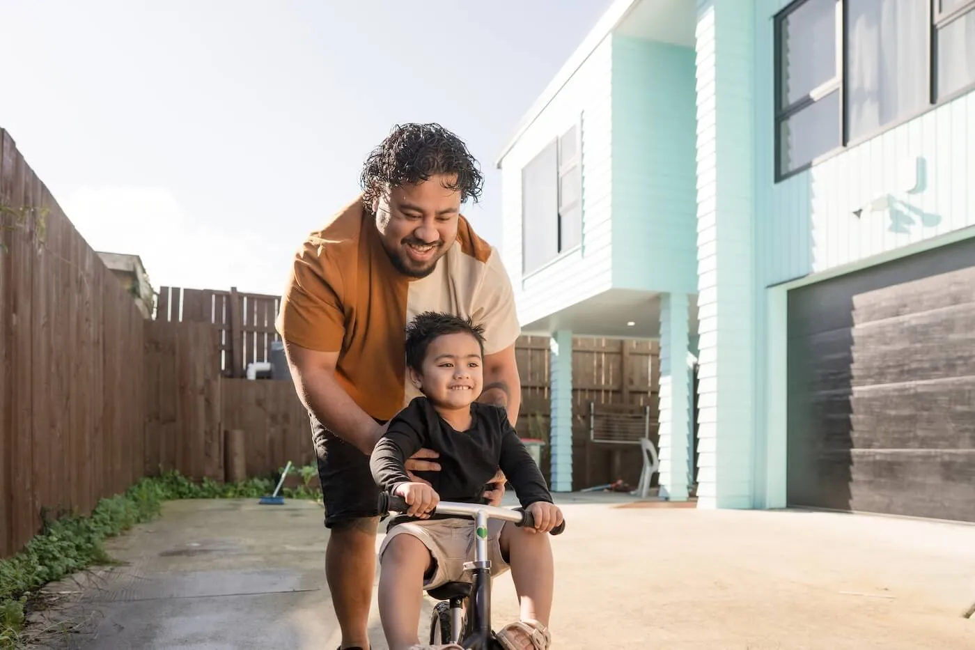 Happy father teaching his toddler son to ride a bicycle on a sunny day