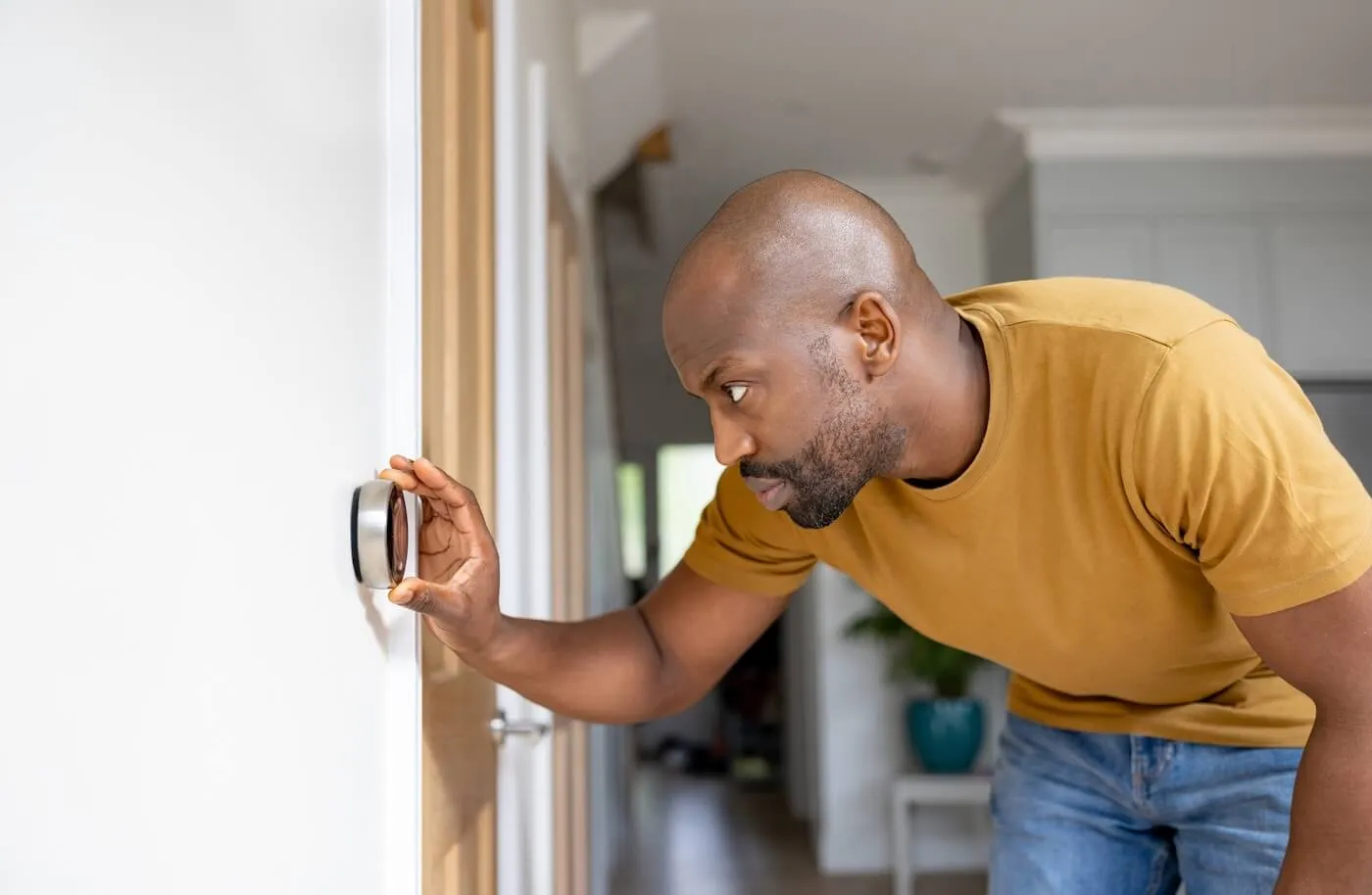 Man adjusting the temperature on the smart thermostat of his house