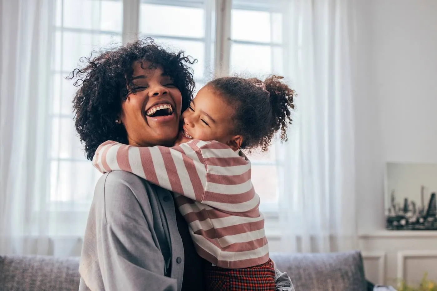 Young daughter hugging her smiling mother at home