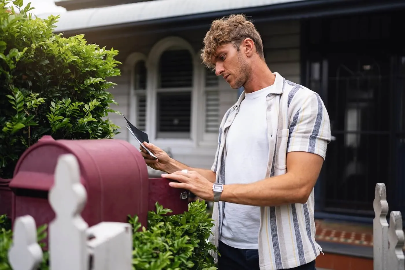 Focused man checking a mailbox outside of his house