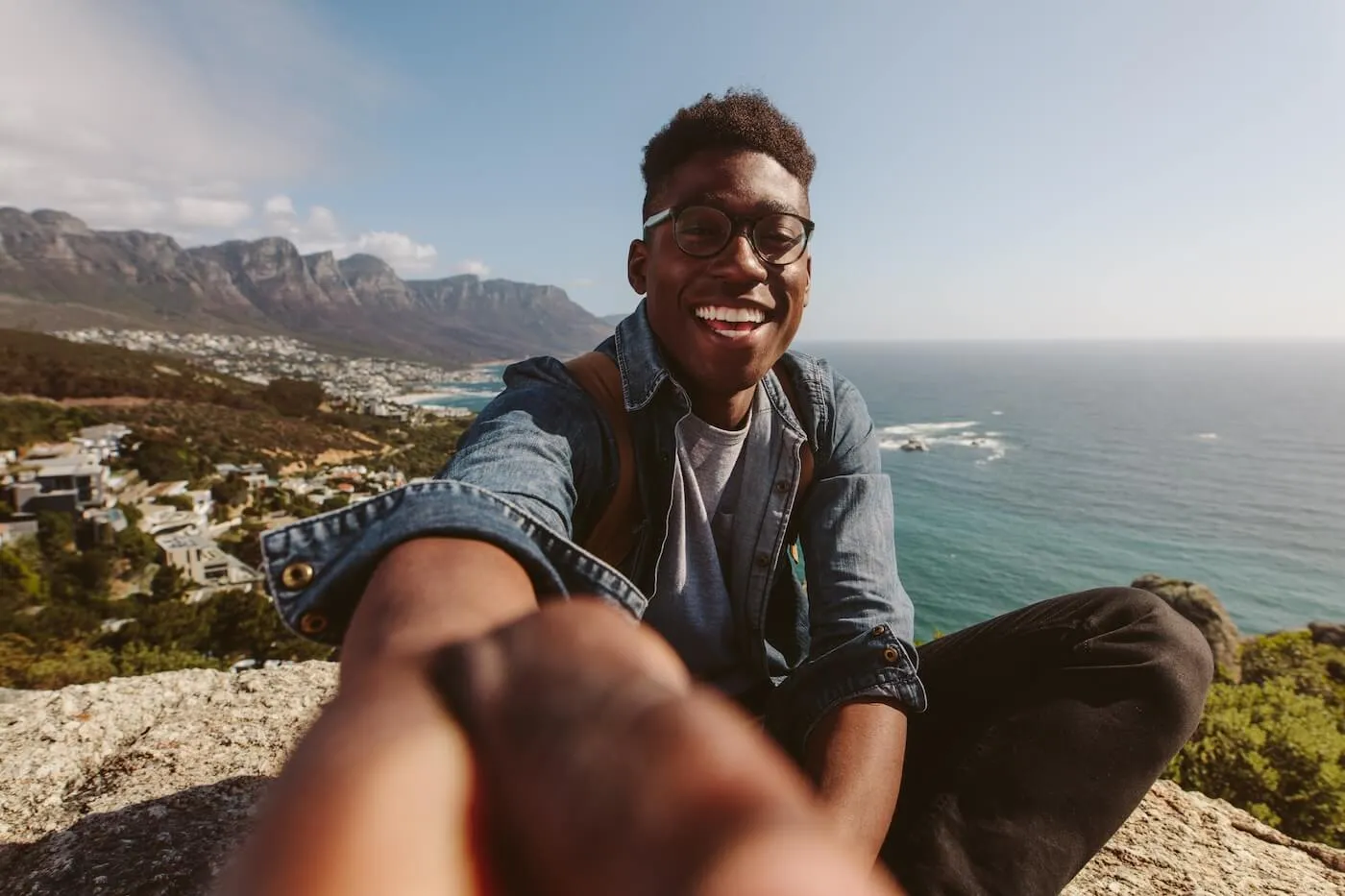 Smiling young man with a backpack takes a selfie with a panoramic sea view