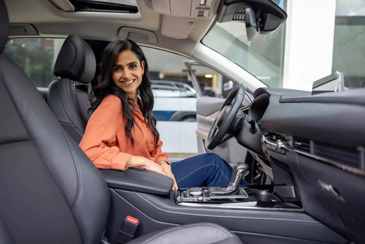 Smiling young woman sitting in her new car