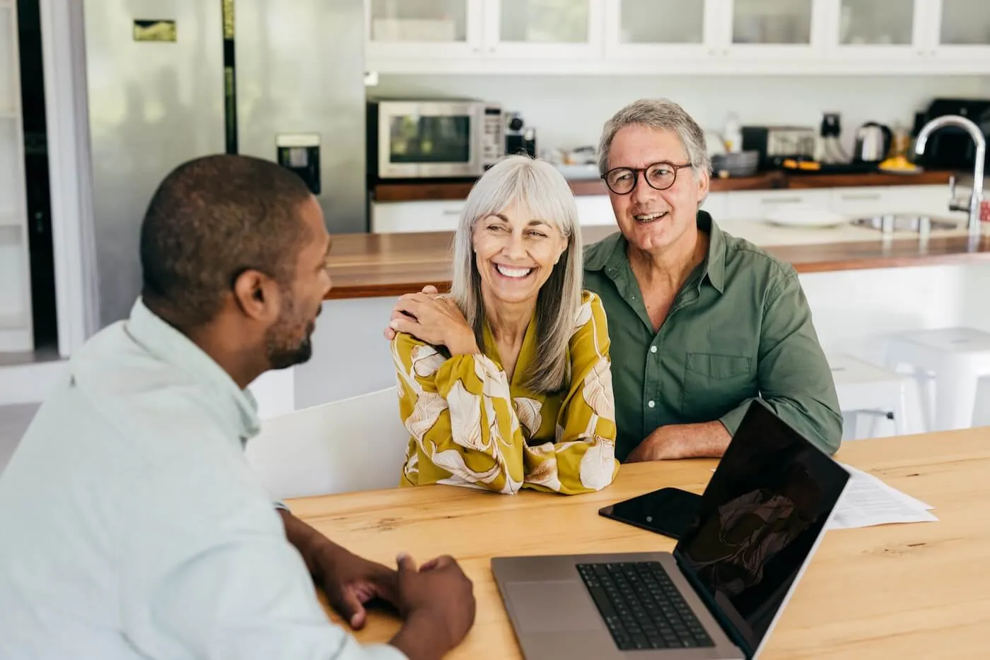 Senior couple having a chat with a male financial advisor in their kitchen