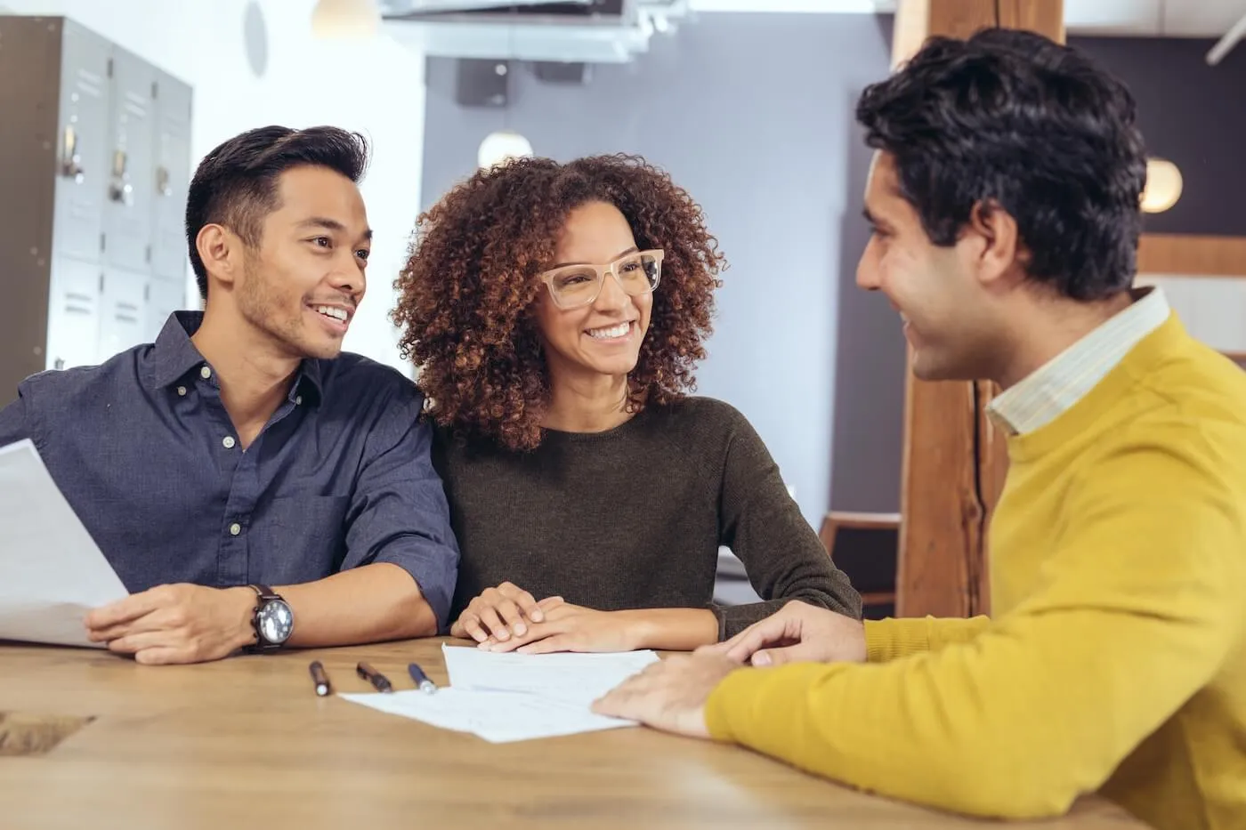 Happy couple discussing their mortgage options with a male lender