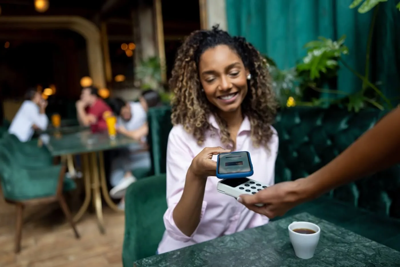 Smiling woman paying with her phone in the cafe