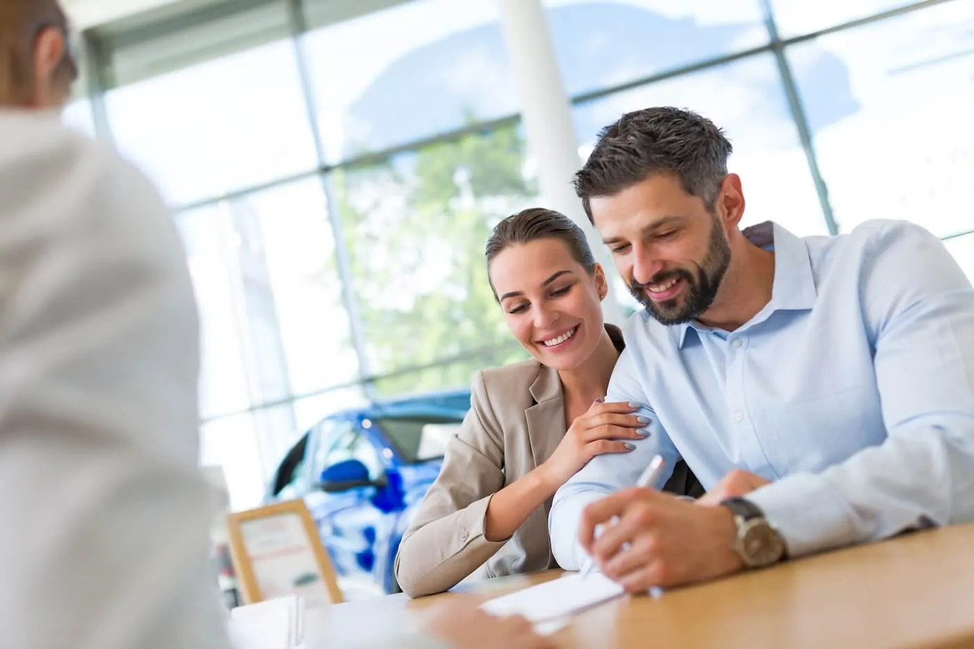Young couple discussing cash-out auto refinancing with the dealership agent