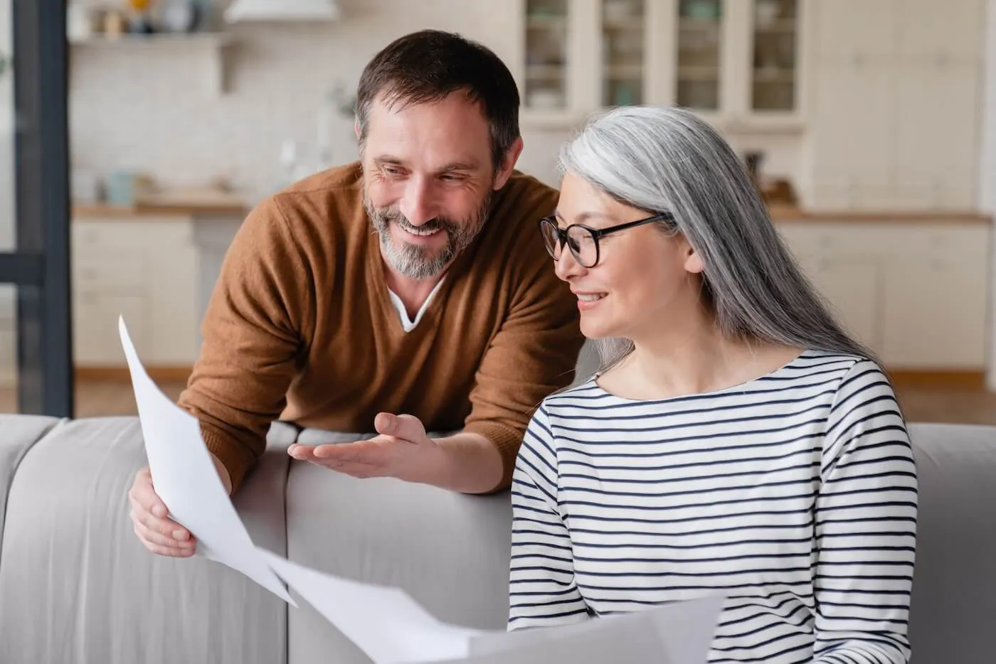 Happy mature couple reviewing the documents in the living room
