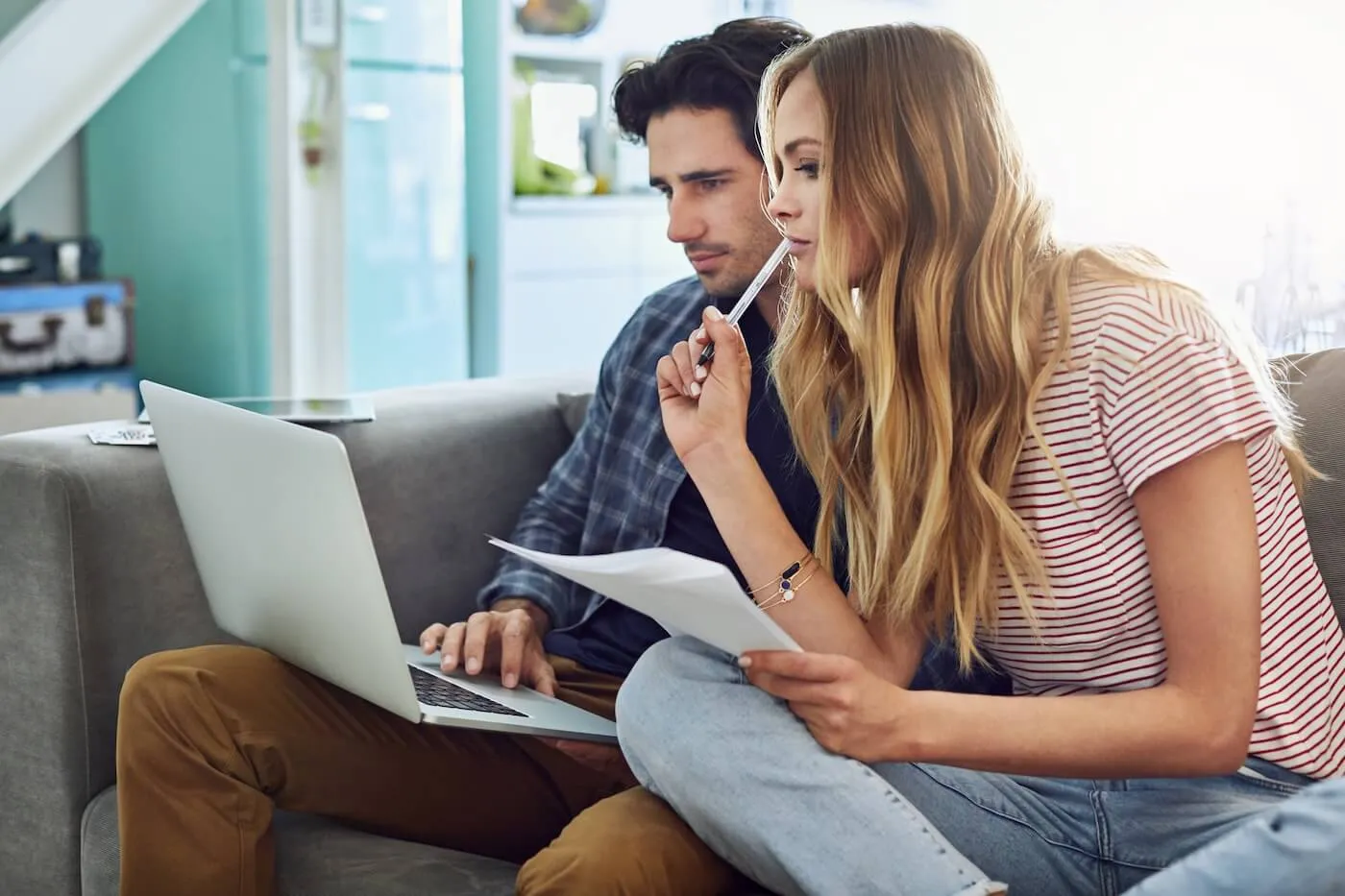 Focused young couple sitting at home, looking at a laptop together while reviewing their finances