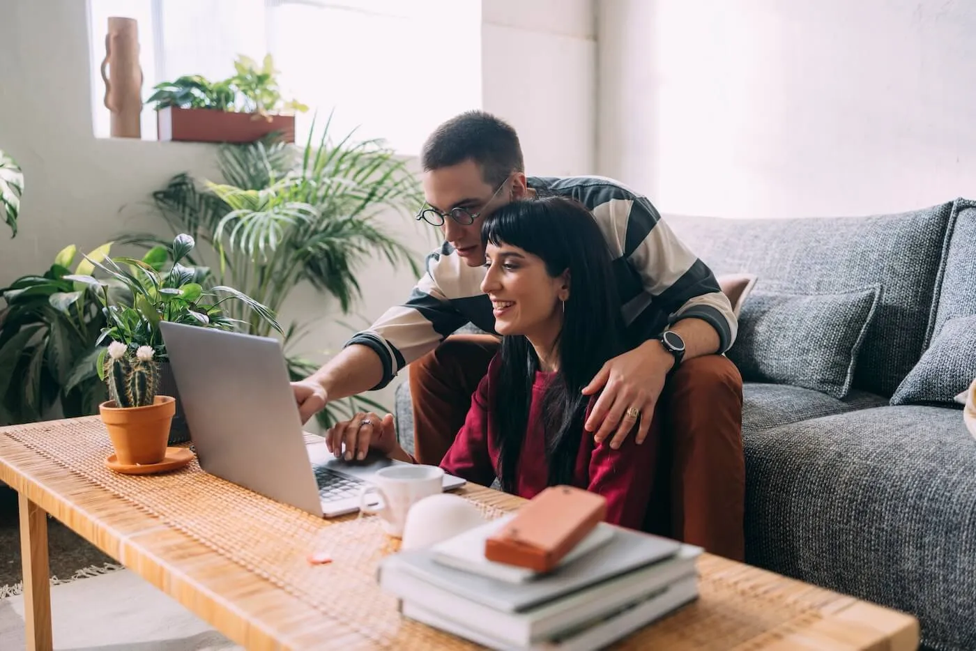 Couple seated in a cozy living room, looking at a laptop screen.