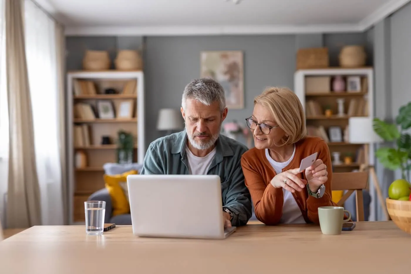 Mature couple using their laptop and a credit card at home