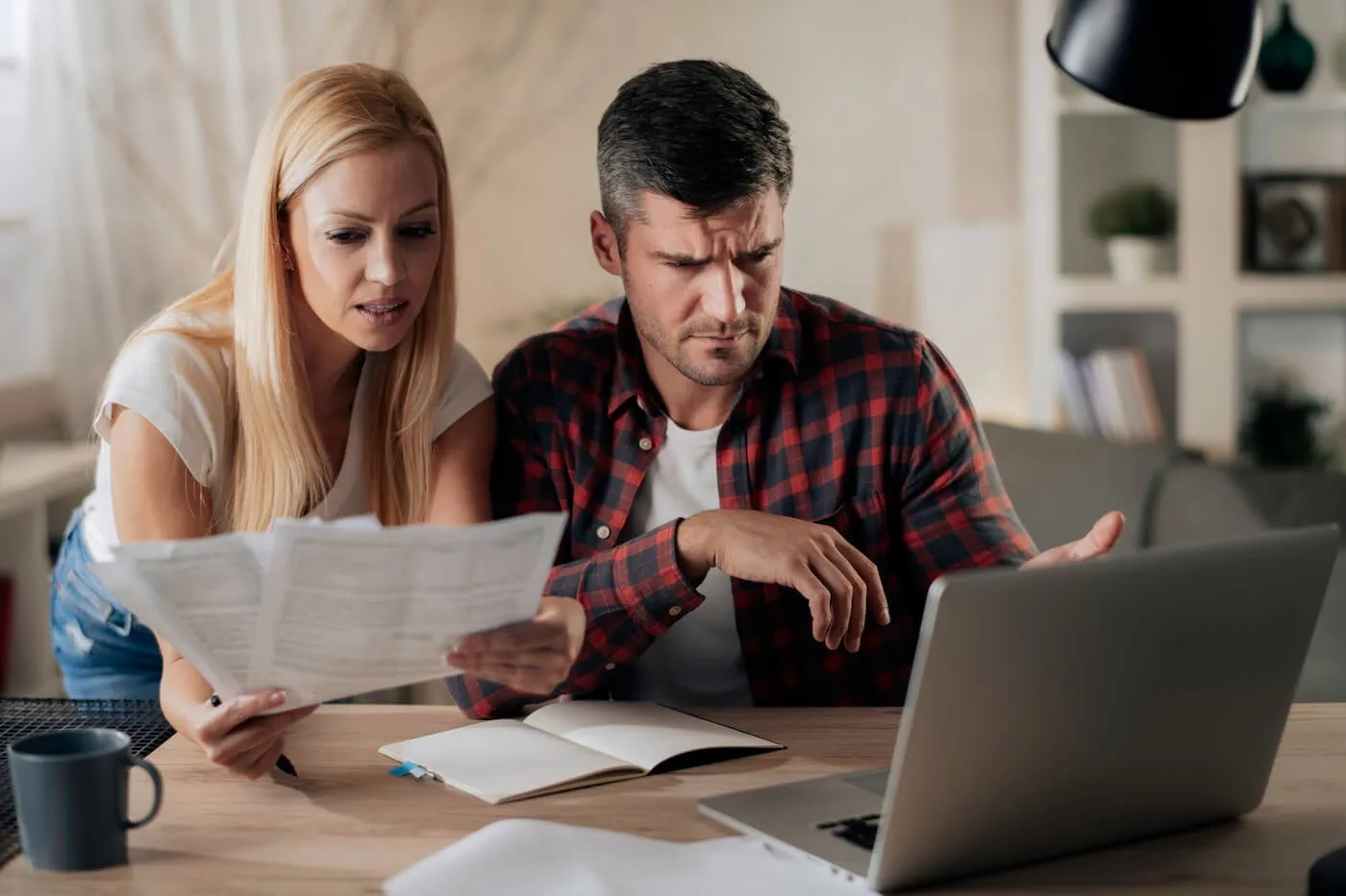 Concerned couple reviewing bills together while using a laptop at home