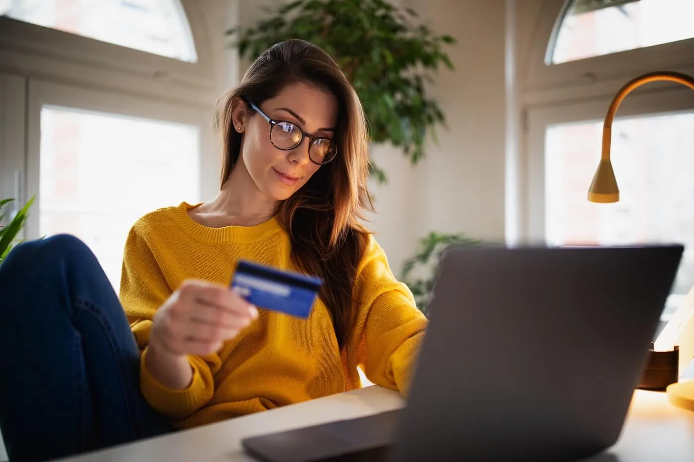 Young woman holding a credit card while using her laptop