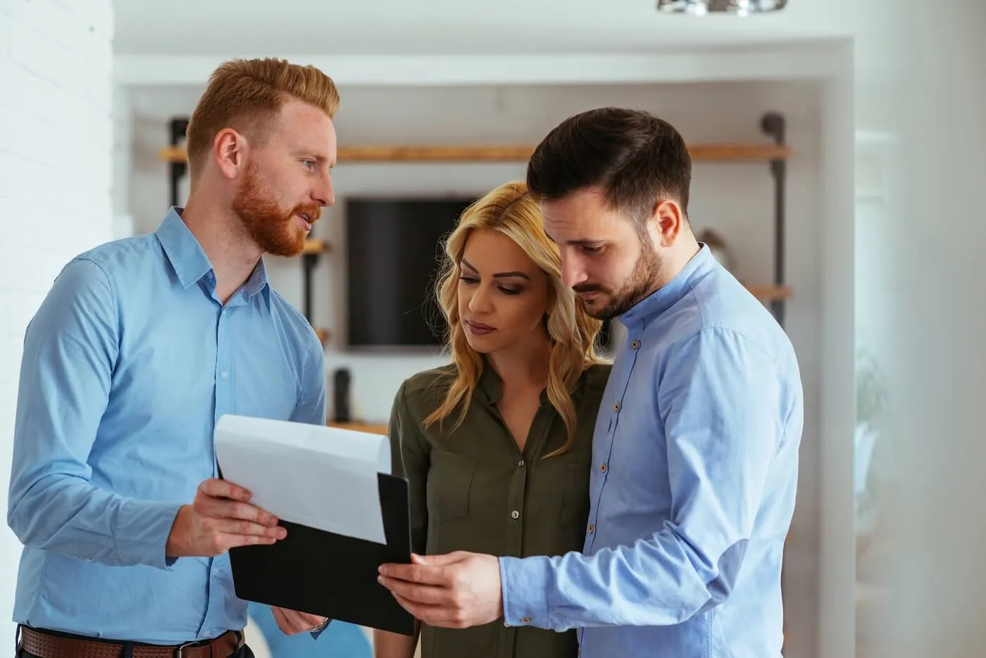 Male real estate agent is showing the documents to a young couple