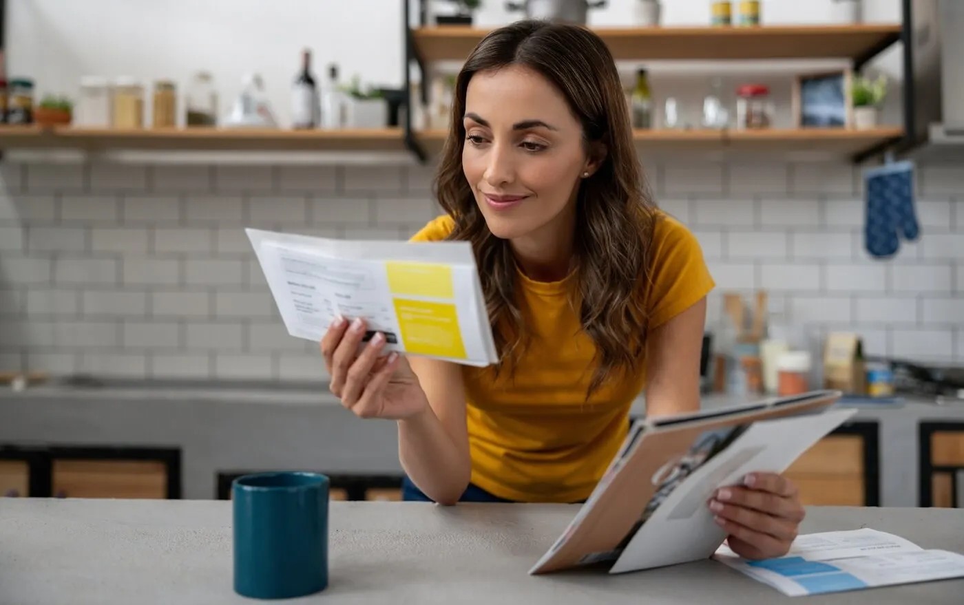 Smiling woman reviewing her mail in the kitchen