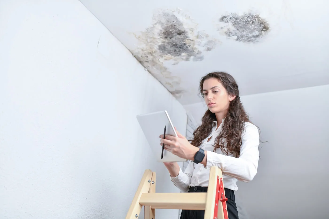 Female claim adjuster inspecting the damaged ceiling