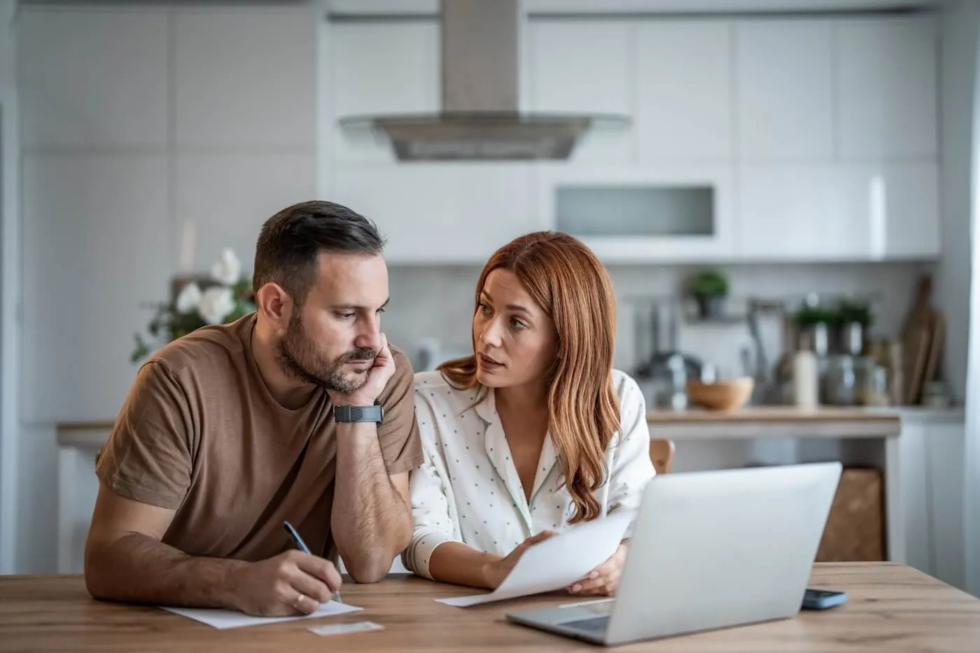 Focused couple discussing CD rates and using a laptop in the kitchen