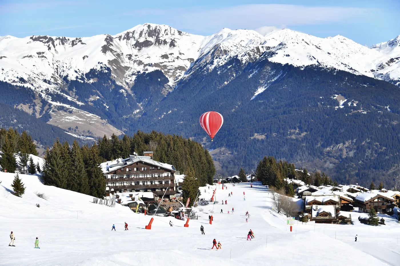 Winter scenery with hot air balloon in air over slopes of French ski resort.