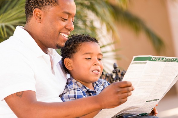 A father and son reading the newspaper.
