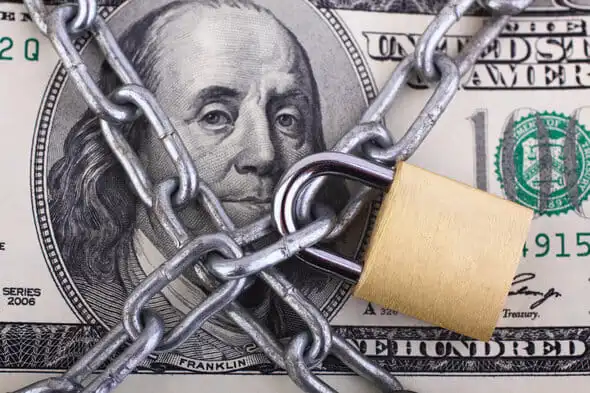 A one hundred dollar bill behind a chain and lock.
