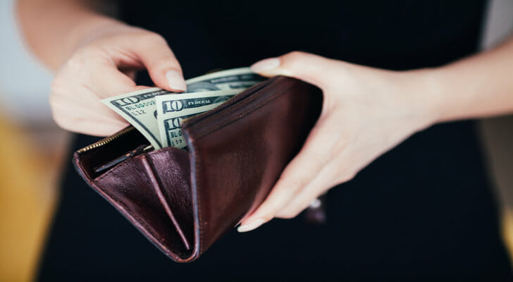 Close-up of a person counting cash in their wallet.