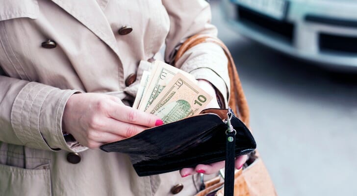 A woman counting cash before putting it in her wallet.