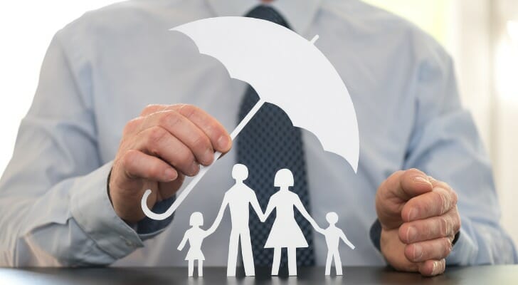 Man holds tiny model umbrella over stick figures representing a family