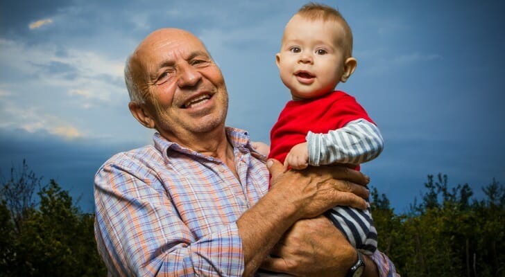 A grandfather holding his grandson, having reviewed the benefits of a trust vs. estate for his family and legacy.