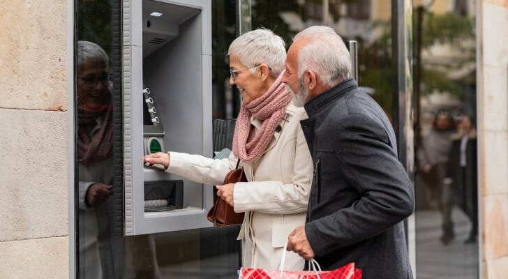 A senior couple withdrawing money from an ATM.
