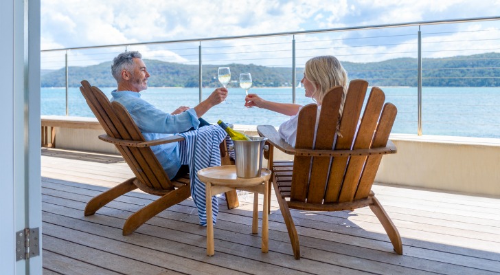 A married couple toasts to their retirement on a cruise ship balcony.